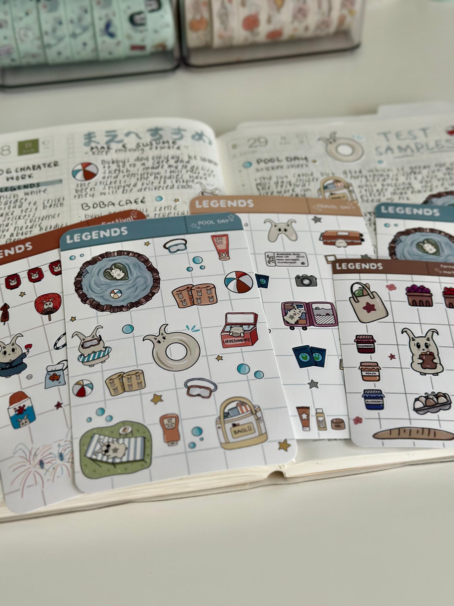 Pool day sticker sheet, travel day, and festival sticker sheet laying on top on my journal.