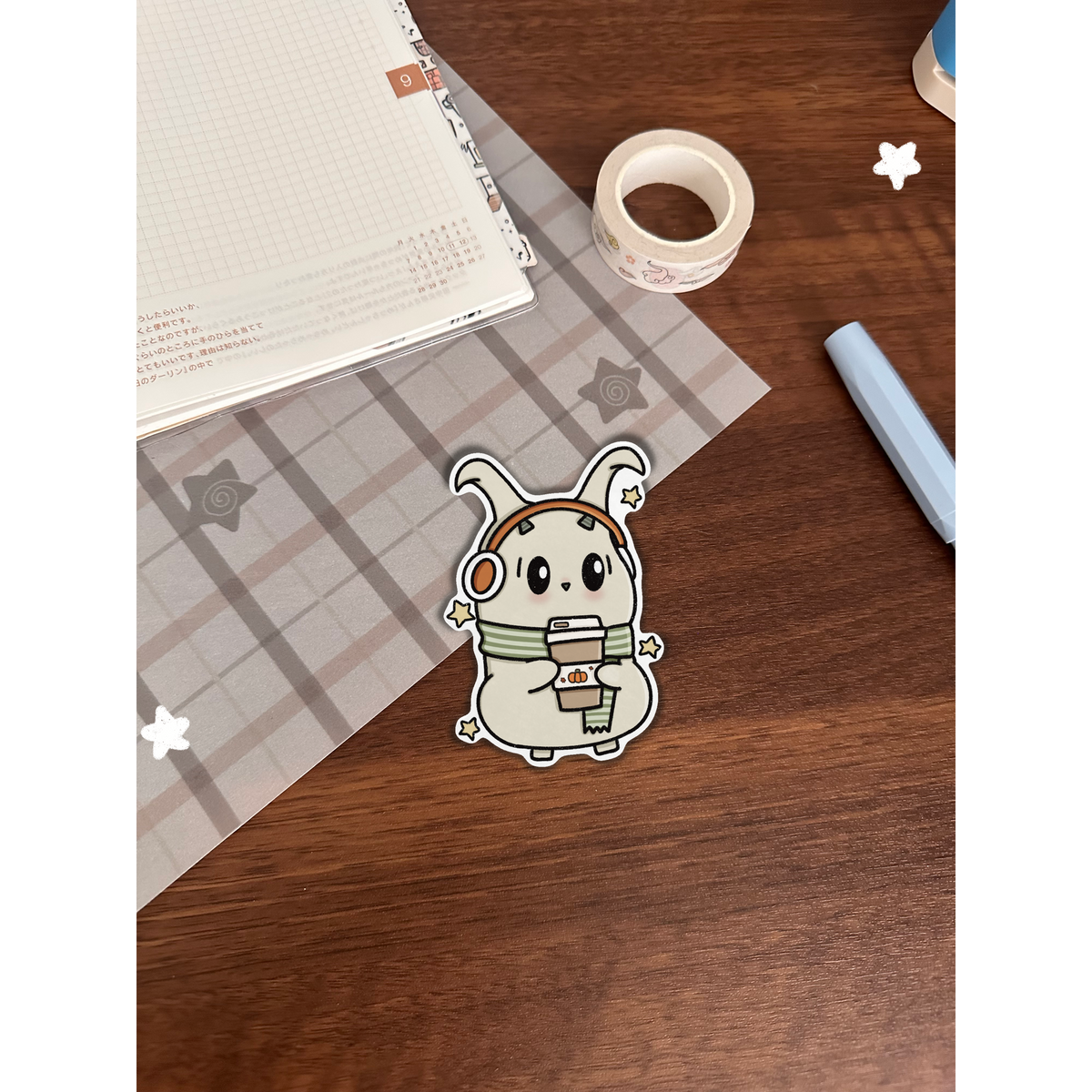 Cozy lün with scarf and ear muffs on top of a wooden desk with journal 