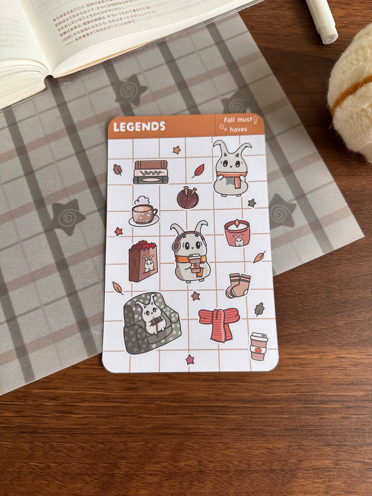 Fall must haves sticker sheet that has scarfs, coffee, etc on top of a wooden desk 