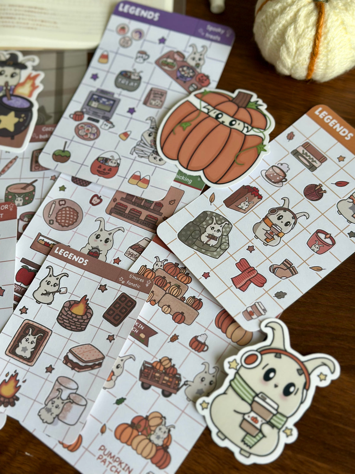 A variety of Fall sticker sheets and die cuts on top of a wooden desk  