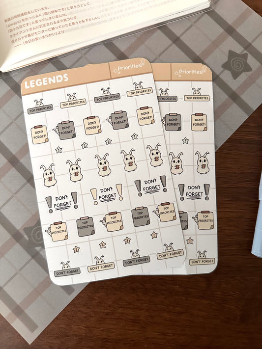 Two planner stickers sheets that have “priorities” and don’t forget” sticky note stickers and lün popping up 