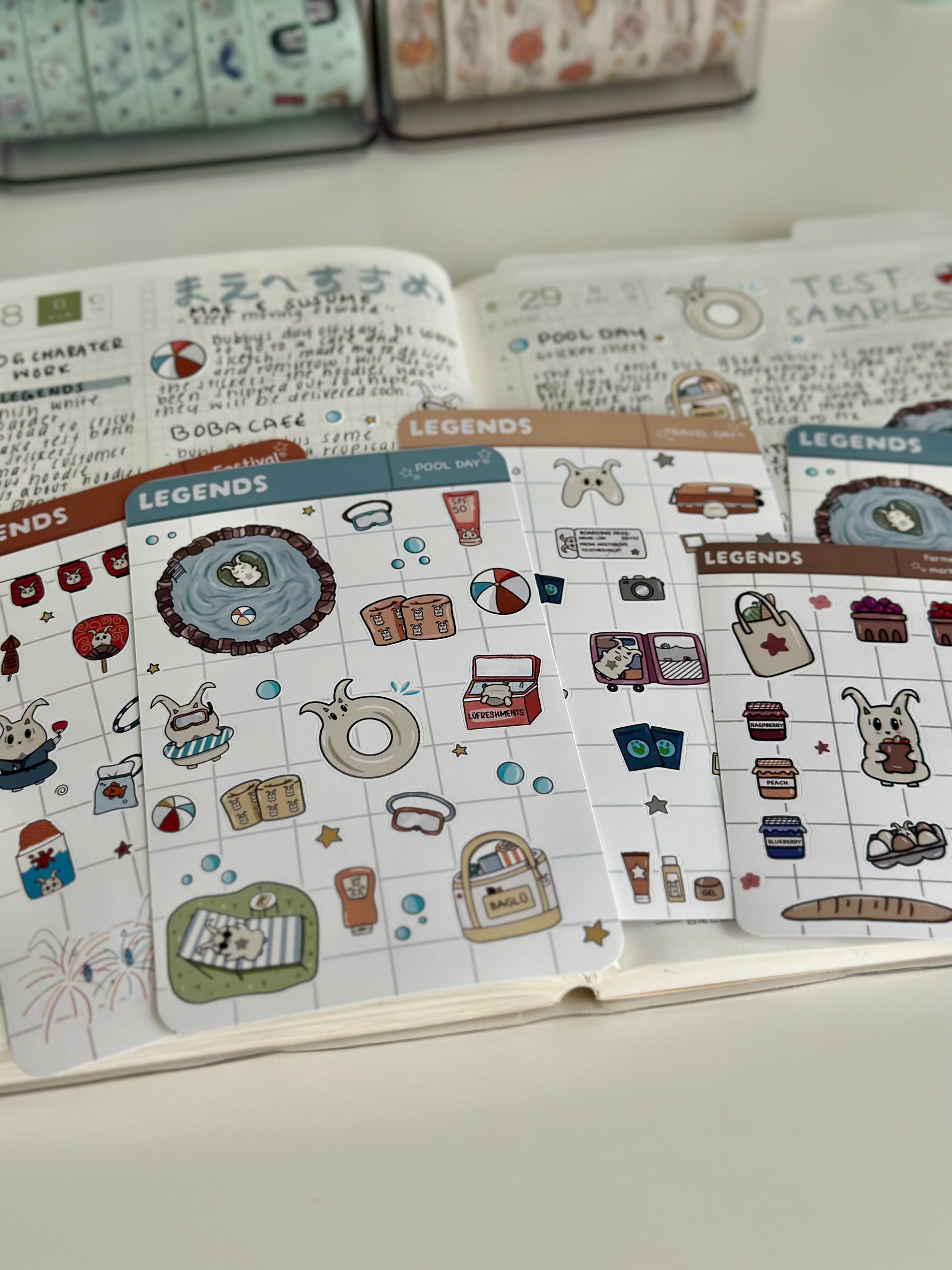 Pool day sticker sheet, travel day, and festival sticker sheet laying on top on my journal. 