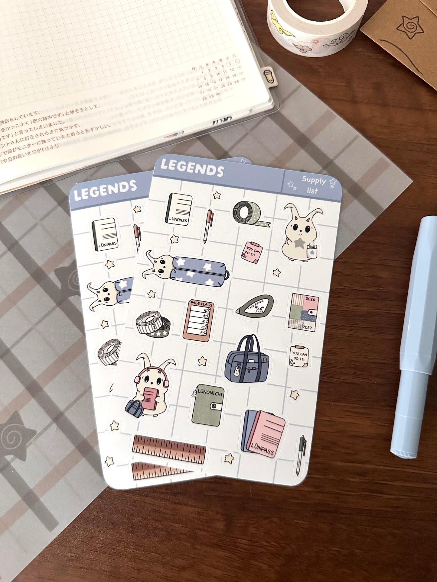 Sticker sheet with back to school supplies and our character lün. Sheet is on top of a wooden desk 