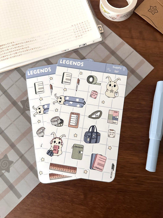 Sticker sheet with back to school supplies and our character lün. Sheet is on top of a wooden desk 
